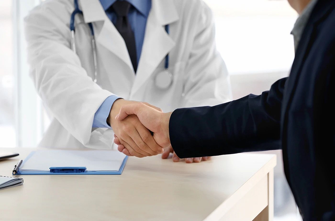 Physician shaking hands with a person in a suit